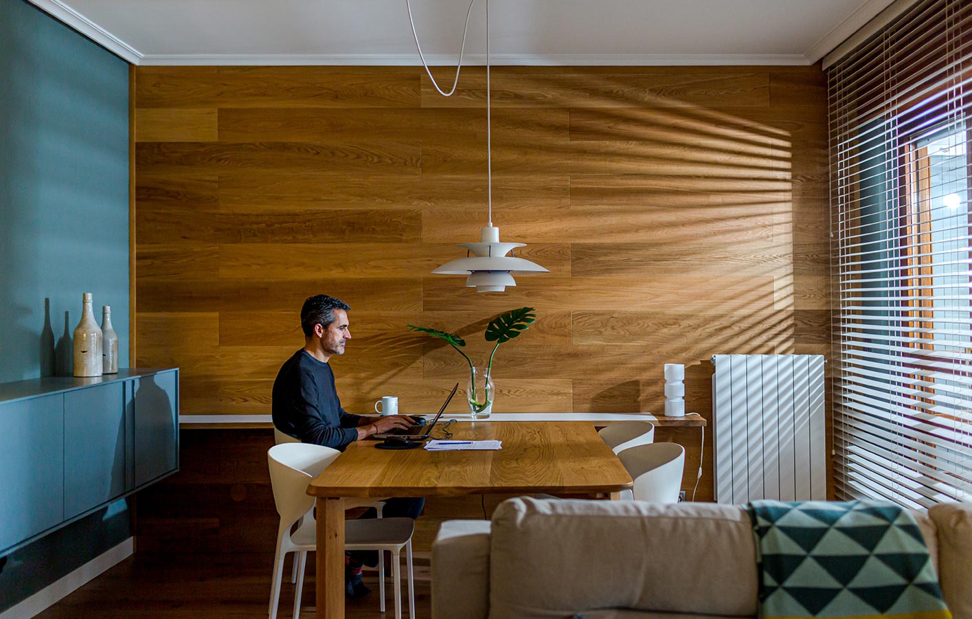 Moderne Wände aus Holz - Paneele und Holzpaneel Mann sitzt im Homeoffice am Holztisch vor einer Holzwand